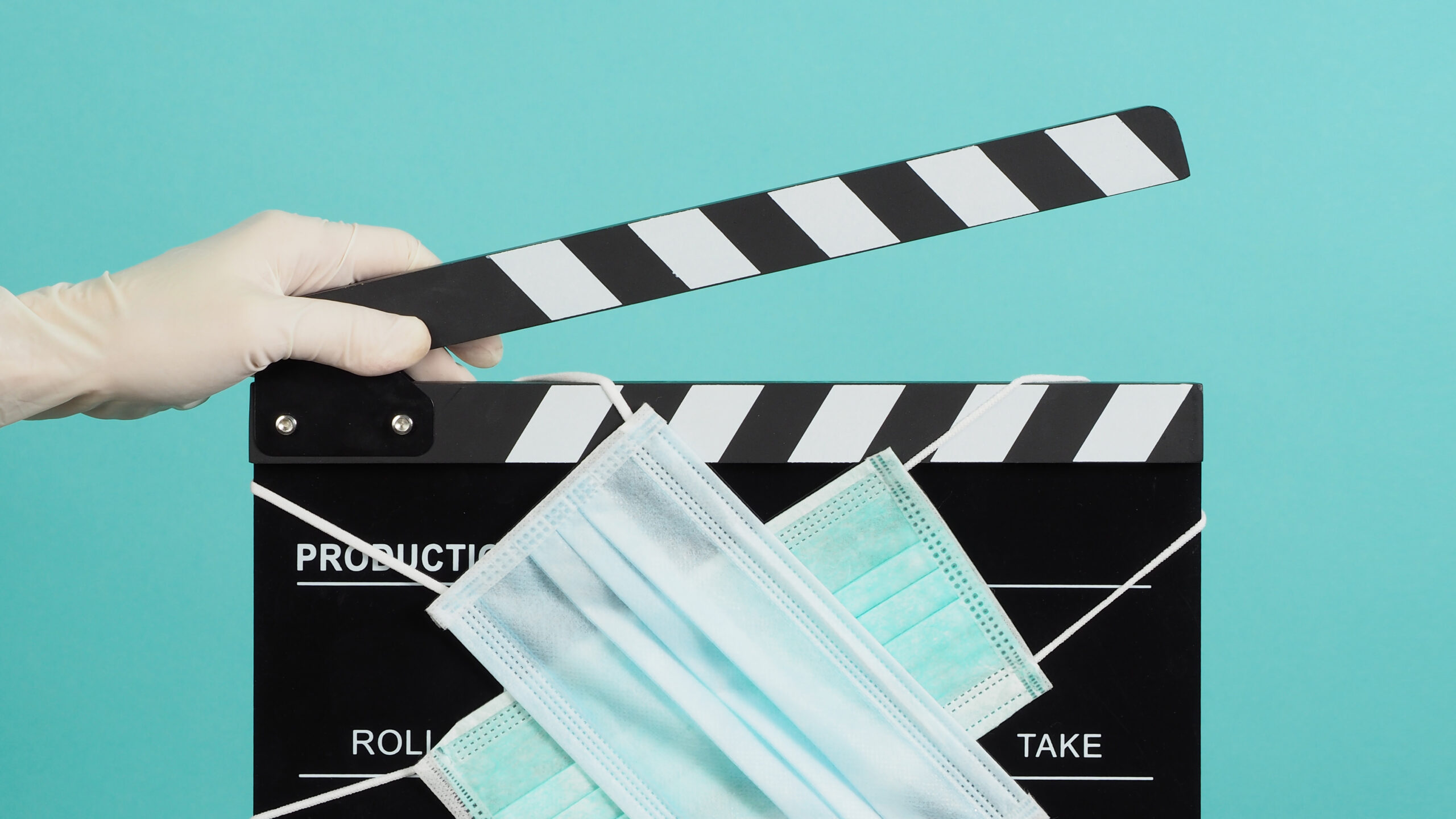 Medical experts symbolized by surgical gloves holding a film clapperboard with medical masks, highlighting healthcare accuracy in filmmaking.