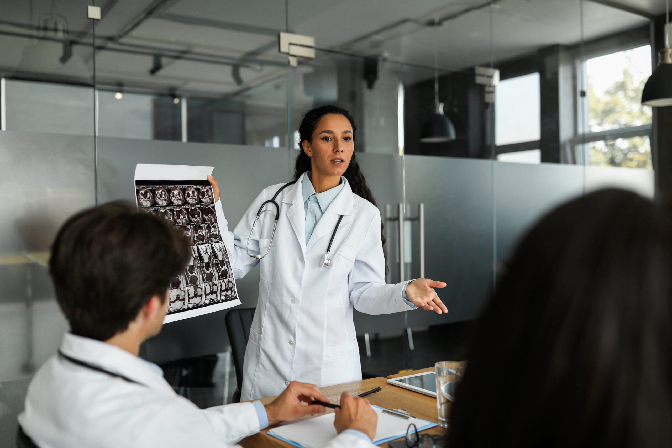 Medical experts led by a doctor presenting MRI scans to colleagues during a professional clinical discussion.