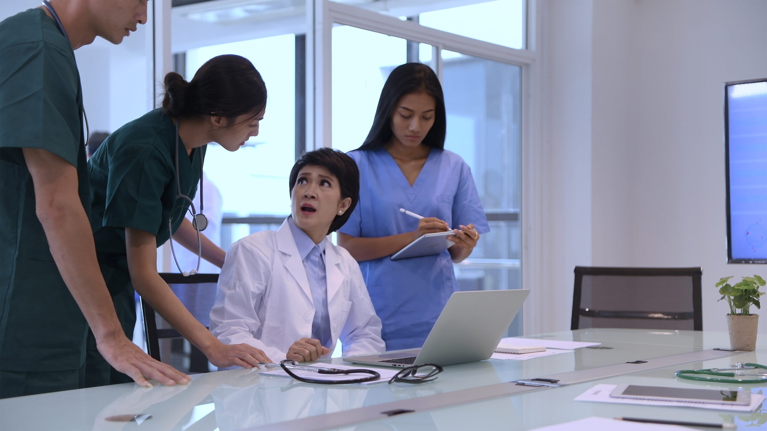 Medical experts in discussion around a conference table reviewing patient data and case files for clinical or legal analysis.