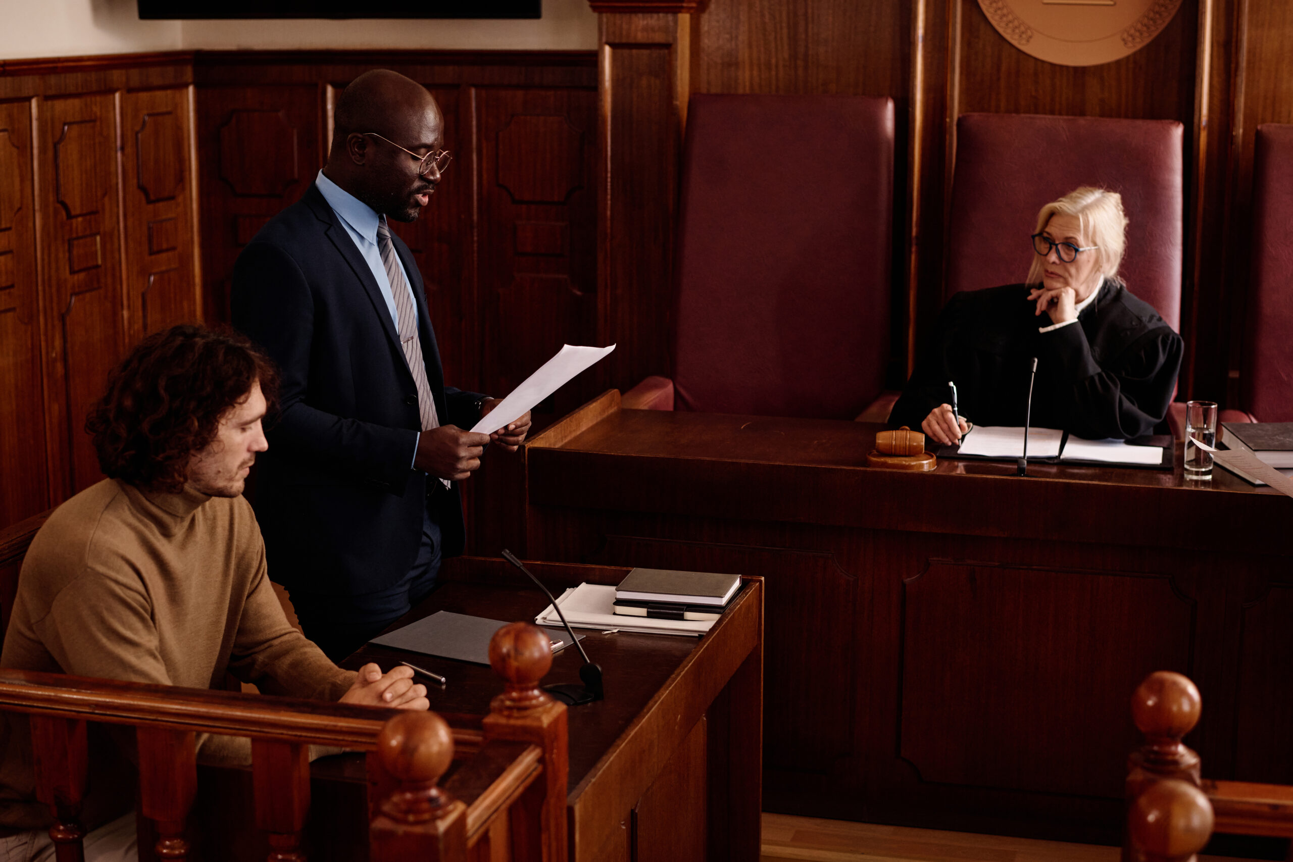 Medical experts observing courtroom proceedings as a judge reviews testimony during a legal hearing.