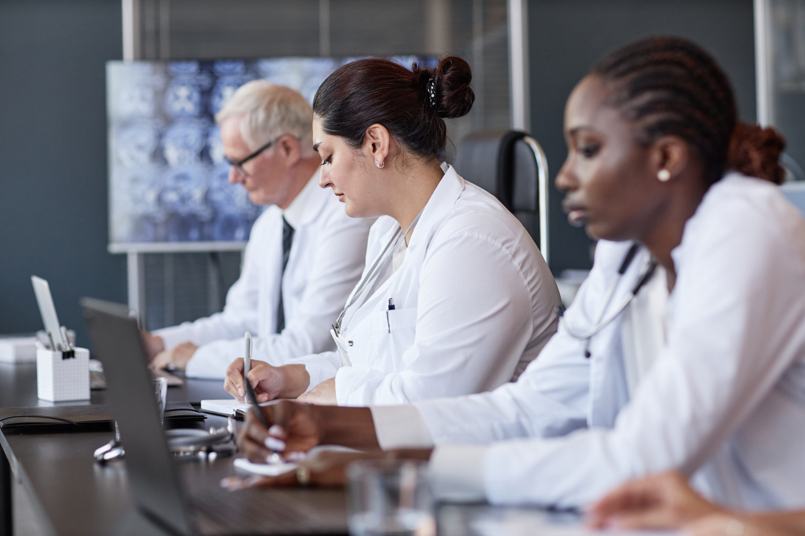 Medical experts attending a professional case review meeting while taking notes and analyzing documentation.